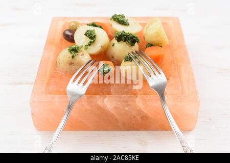 Des pommes de terre et les carottes avec la sauce Chimichurri vert et fourches vintage servi sur bloc de sel rose carré hymalayan closeup Banque D'Images