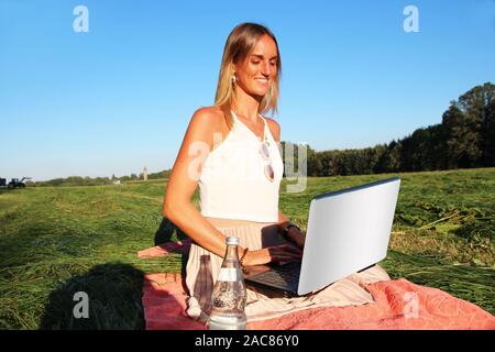 Belle jeune femme travaillant à l'extérieur sur son ordinateur portable avec connexion Internet haut débit Banque D'Images