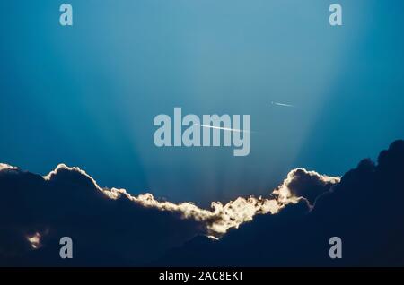 Ciel bleu avec des nuages spectaculaires, les rayons du soleil et avions passant Banque D'Images