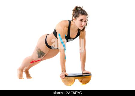 Kinesio tape girl, l'exercice pousées. Belle Jeune femme sport faisant pousser l'exercice en pleine longueur isolé sur fond blanc. Thème Banque D'Images