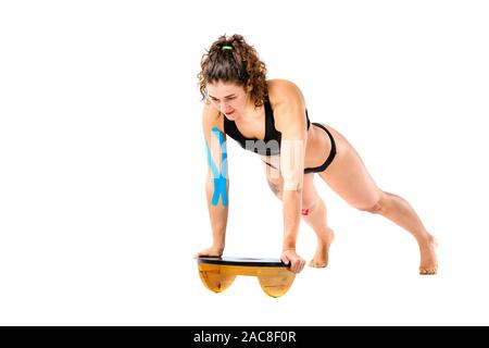 Kinesio tape girl, l'exercice pousées. Belle Jeune femme sport faisant pousser l'exercice en pleine longueur isolé sur fond blanc. Thème Banque D'Images