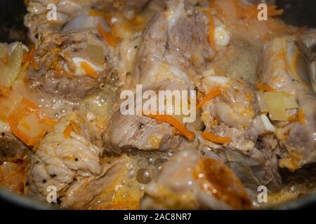 Côtes levées de porc mariné aux épices mijotée dans une casserole avec les oignons et les carottes. La cuisine maison. Close up. Banque D'Images