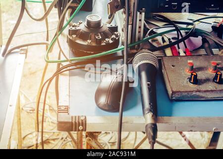 Un vieux microphone à condensateur noir et une souris noire placée sur une table de contrôle audio avec un câble emmêlé dans l'air extérieur utilisé pour les annonces. Banque D'Images