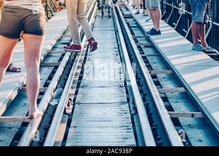 Les touristes à pied à travers l'ensemble de rail de chemin de fer d'un côté à l'autre côté tout en se rendant sur le pont de la rivière Kwai à Kanchanaburi, Thaïlande. Banque D'Images