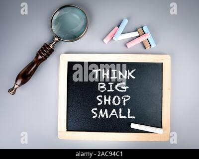 Think Big Shop petit. Tableau sur lequel un texte, loupe sur une table gris Banque D'Images