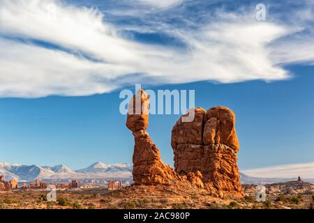 Des oiseaux comme les nuages vaporeux sur Balanced Rock emblématique contre la La Sal Mountain en parc national Arches dans Moab, Utah. Banque D'Images