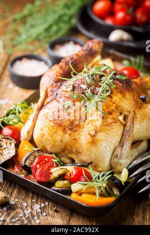 Poulet entier cuit au four avec légumes et herbes close-up sur une plaque sur une table. Banque D'Images