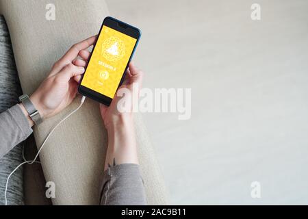 Les mains de jeunes femmes avec le smartphone attente de téléchargement de vidéo Banque D'Images