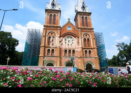 HO CHI MINH ville, VIETNAM - le 15 novembre 2019. La Cathédrale Notre Dame de Saigon avec des fleurs en premier plan Banque D'Images