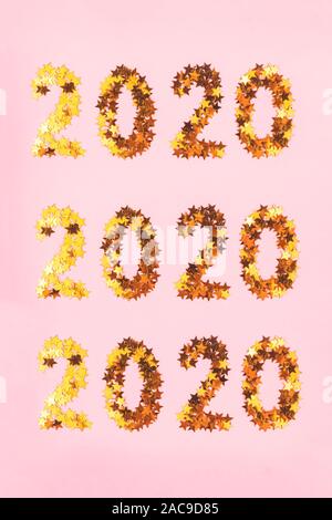 2020 Nouvelle année bordée de chiffres de golden glowing stars sur un fond rose vif. Collage de trois numéros identiques. Haut de la vue, télévision lay. Banque D'Images