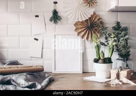 Noël encore la vie. Cadre photo en bois blanc et les cartes de vœux papier avec la maquette, eucalyptus, jacinthe en pot de fleurs et de l'emballage-cadeau Banque D'Images