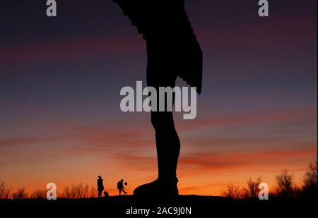 Un garçon joue avec un ballon de football à l'Ange du Nord à Gateshead après le coucher du soleil. Banque D'Images