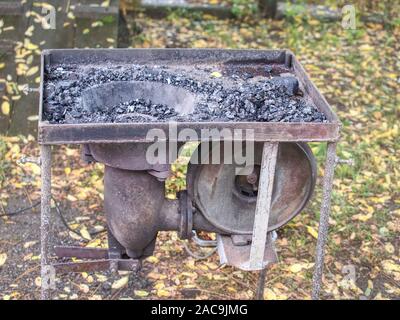 Four portable ouvert de maréchaux-ferrants. La combustion du charbon dans le four, éteint le feu dans la région de four de forge, lieu de travail temporaire. Concept d'backsmithing Banque D'Images