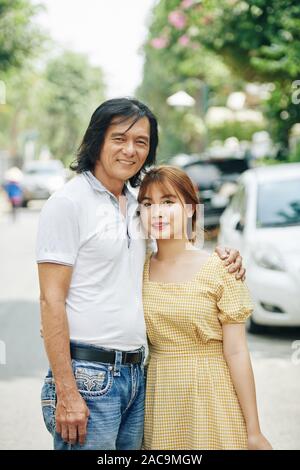 Portrait of middle-aged man posant avec sa jolie fille lorsque debout sur route dans petite ville Banque D'Images