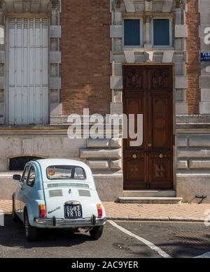 Fiat 500 stationné à l'extérieur du grand bâtiment de Jarnac, Charente, France Banque D'Images
