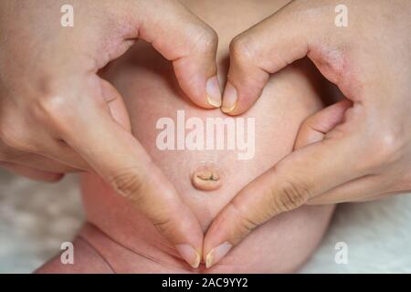 Close up mains rend coeur sur le ventre de bébé nouveau-né Banque D'Images