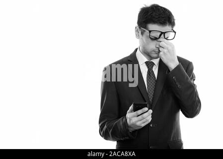 Studio shot of young businessman wearing eyeglasses fatigué en maintenant le téléphone mobile Banque D'Images