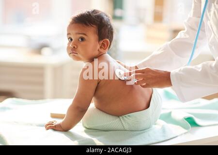Cute toddler assis sur la table tout en écoutant son pédiatre à l'hôpital de pulsation Banque D'Images