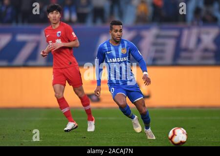 Joueur de football brésilien Alex Teixeira de Jiangsu Suning F.C., droite, conserve la balle au cours du 30e match de football chinois Super League (CSL) contre Tianjin Tianhai à Nanjing city, Jiangsu province de la Chine de l'Est, 1 décembre 2019. Shanghai Suning défait Tianjin Tianhai avec 2-0. Banque D'Images