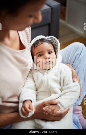Mignon bébé africain garçon couché sur les mains de sa mère et essayer de dormir pendant qu'ils assis à la maison Banque D'Images