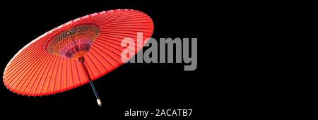 Parapluie japonais rouge sur fond noir panoramique with copy space Banque D'Images