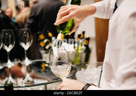 Une offre d'une bouteille de vin se verse dans un verre lors d'un événement, mariage ou du congrès Banque D'Images