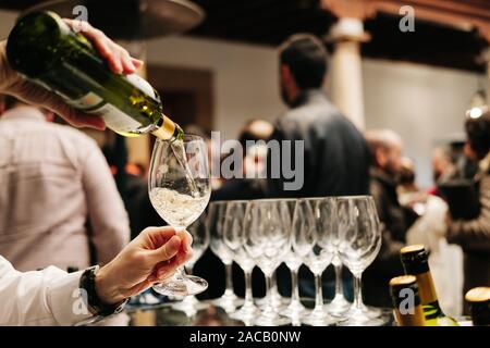 Une offre d'une bouteille de vin se verse dans un verre lors d'un événement, mariage ou du congrès Banque D'Images