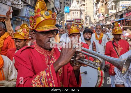 Accompagnant une procession en l'honneur de dieu Venkateshwara (Balaji), l'uniforme rouge des musiciens jouent leurs trompettes et timbales ; Bhuleshwar, Mumbai, Inde Banque D'Images