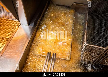 Chips dans une friteuse à graisse profonde dans une boutique de poissons et de copeaux au Royaume-Uni Banque D'Images