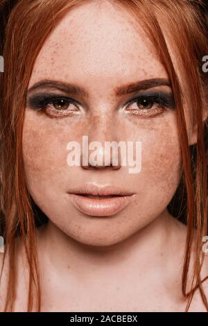 Close-up portrait of beautiful natural woman avec des taches de rousseur sur son visage et yeux smoky bleu scintillait le maquillage. Coiffure rouge. Studio Banque D'Images