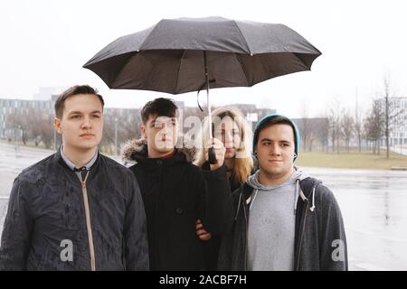 Groupe de jeunes adolescentes urbaines dans un éventail d'amis dans la pluie Banque D'Images