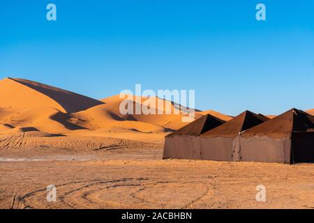 Camp de tentes de luxe brown dans Sahara Merzouga, Maroc sur une journée ensoleillée avec des dunes de sable sur l'arrière-plan Banque D'Images