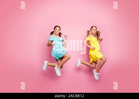 Full Size photo du profil de deux petites soeurs d'amitié modèles dames haut saut pressé accueil vacances d'été porter des robes jaune bleu rose isolé Banque D'Images