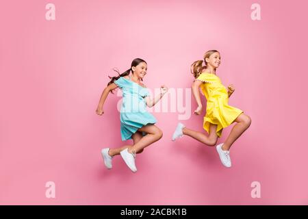 Profil complet du corps photo de deux petits modèles dames amitié haut saut pressé accueil vacances d'abord porter robes jaune bleu rose isolé Banque D'Images