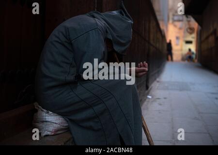 Un pauvre mendiant dans l'homme djellaba à capuche traditionnel marocain tenue. fokiya, jellaba. Pauvre mendiant anonyme dans la rue, Maroc Banque D'Images