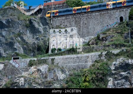 Bâtiment abandonné sur le côté de la colline près de Porto, Portugal avec train de passagers allant au-dessus de lui. Banque D'Images