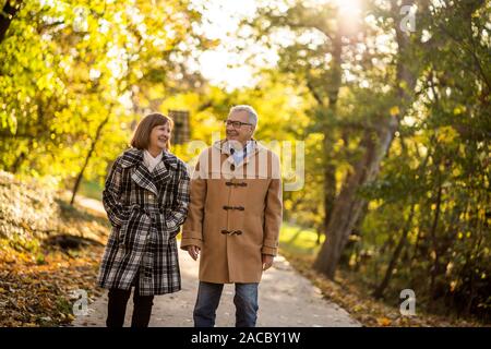 Happy senior couple marche dans le parc en automne. Banque D'Images