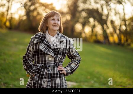 Portrait of senior woman in park en automne. Banque D'Images
