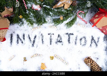 'Invitation' écrit dans la neige avec des ornements de Noël, la paix, la chance, l'amour, heureux, joie - concept carte post Banque D'Images
