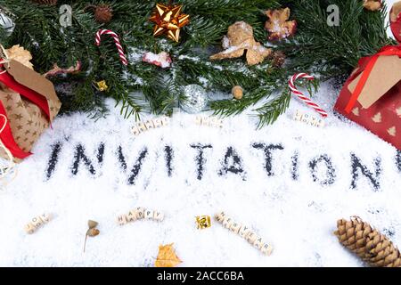 'Invitation' écrit dans la neige avec des ornements de Noël, la paix, la chance, l'amour, heureux, joie - concept carte post Banque D'Images