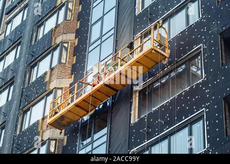 Construction suspendu berceau près de mur de hightower residentaial avec isolation du bâtiment et façade ventilée sur chantier de construction. Engineering Banque D'Images