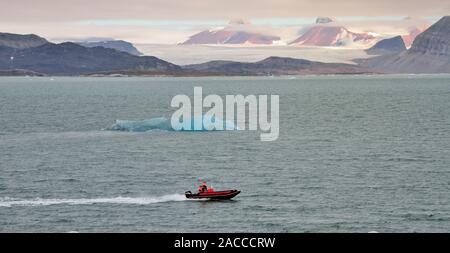 Un petit bateau de la transmission d'un iceberg dans l'Kongsfjorden (King's Bay), en face du glacier Kongsbreen, Spitzberg. Banque D'Images