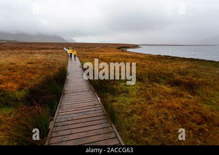 La mère et le fils marche sur signé allée en bois dans le Parc National de Ballycroy un jour de pluie, dans le comté de Mayo, Irlande Banque D'Images