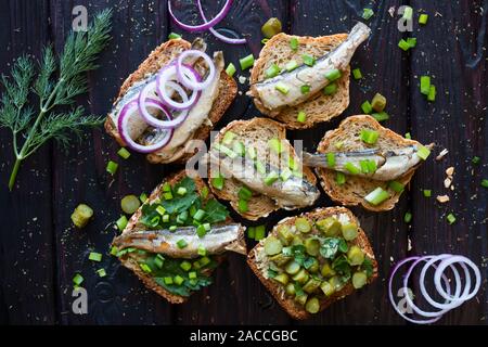 Des sandwichs avec anchois sur un arrière-plan le fenouil et verts sur fond noir Banque D'Images