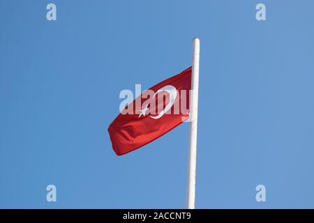 Drapeau turc soufflant contre un ciel bleu Banque D'Images