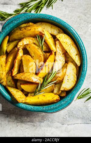 Quartiers de pommes de terre au four au romarin dans un plat bleu. La nourriture végétalienne saine concept. Banque D'Images