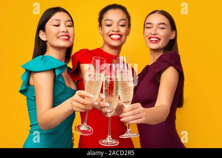 Trois filles avec Champagne ayant partie Clinking Glasses In Studio Banque D'Images