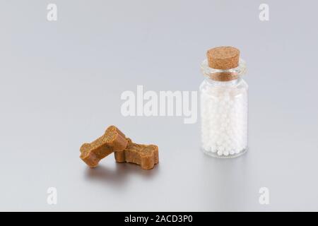 Globules homéopathiques pour l'animal dans une bouteille en verre et le traite comme les os Banque D'Images