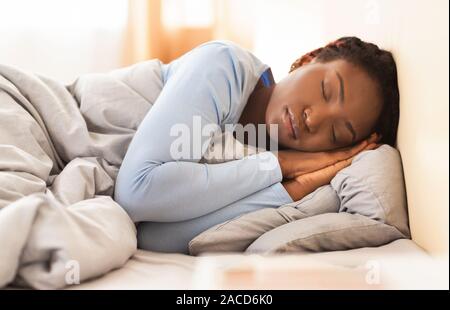 Black Girl Holding couchage plié mains près de visage dans la chambre Banque D'Images