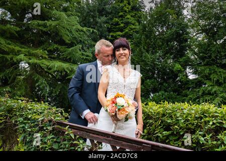 Mariés et mariés posent pour leurs photos après la cérémonie dans les jardins de l'hôtel Manor, B & B à Cheadle, Stoke on Trent, Staffordshire, jour du mariage Banque D'Images